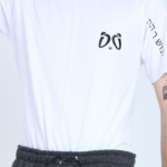 Primer plano de la camiseta blanca Aypanda, mostrando el logo minimalista de ojos de panda en el pecho, texto en hebreo en la manga y un collar de conchas, destacando el diseño auténtico y único.