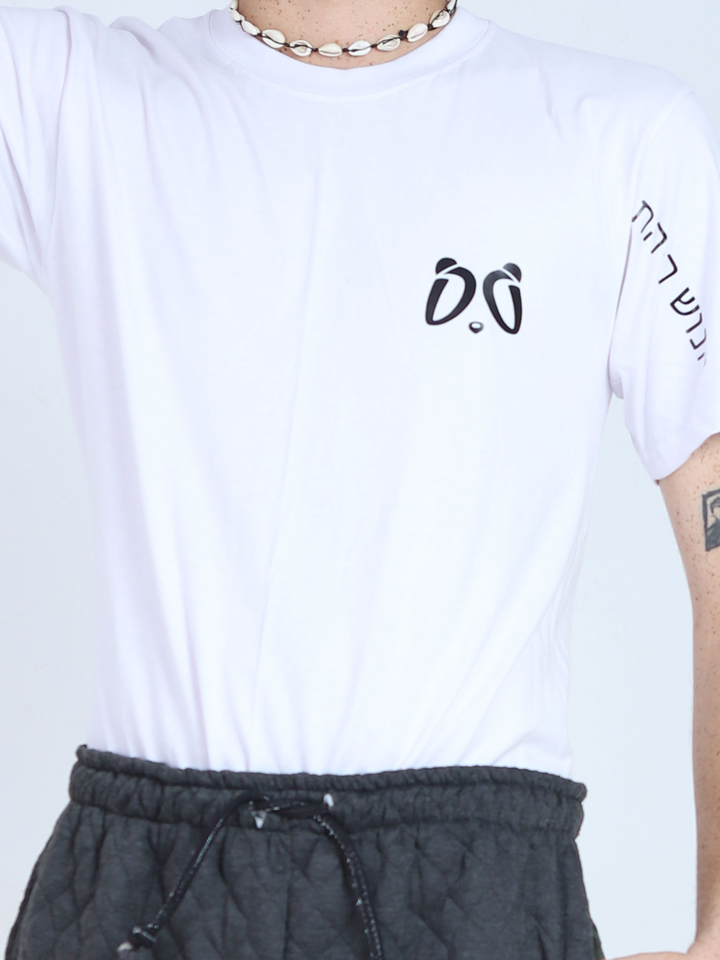 Primer plano de la camiseta blanca Aypanda, mostrando el logo minimalista de ojos de panda en el pecho, texto en hebreo en la manga y un collar de conchas, destacando el diseño auténtico y único.