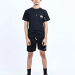 Joven modelo con cabello rizado, vistiendo conjunto Aypanda de camiseta negra oversized y shorts negros deportivos con logo blanco, mostrando estilo casual y libertad.